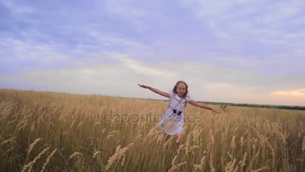 Dívka je teenager, rozevřela náruč jako křídla a běží přes pole s úsměvem. Zpomalený pohyb. - Záběry, video
