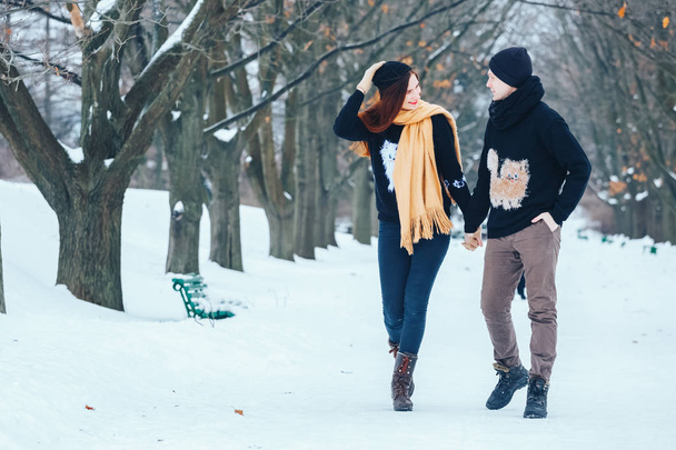 Χαμογελώντας Ζευγάρι περπατά μέσα στο χιονισμένο δάσος μαζί - Φωτογραφία, εικόνα