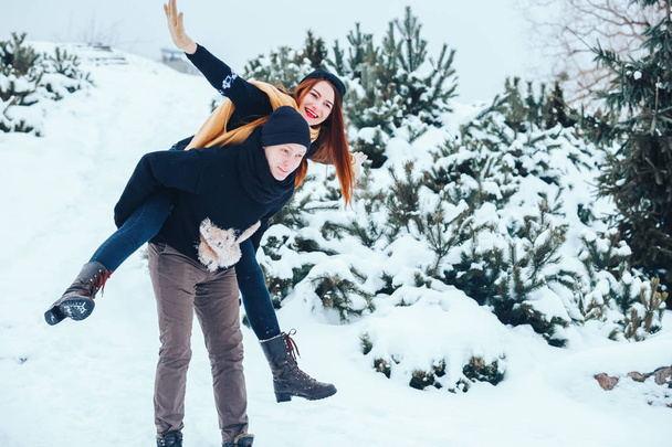 Smiling couple walking in snowy woods together - Valokuva, kuva