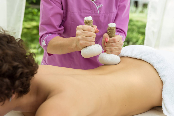 Tajski masaż piłką. Kobieta w dzień SPA coraz tajski masaż ziołowy kompres. - Zdjęcie, obraz