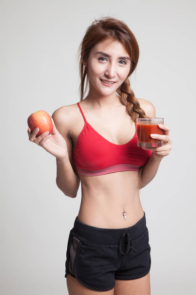 Beautiful healthy Asian girl with tomato juice and apple. - Foto, imagen