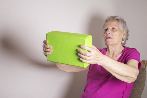 Vanhempi nainen tekemässä kuntoutusharjoituksia joogan lohkolla
 - Valokuva, kuva