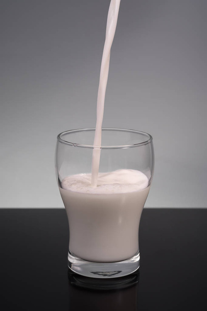 Vaso de leche sobre fondo gris
 - Foto, imagen