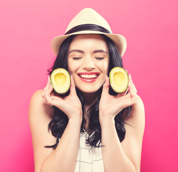 Happy young woman holding avocado halves  - Fotoğraf, Görsel