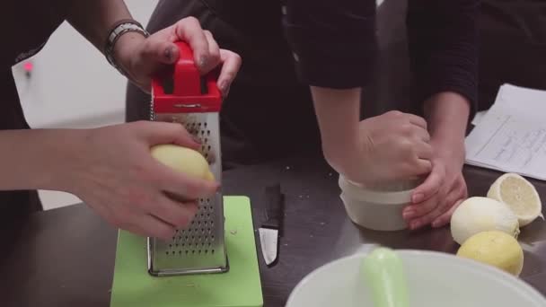 Cozinheiras em aventais usando ralador e espremedor com limões na mesa da cozinha
 - Filmagem, Vídeo