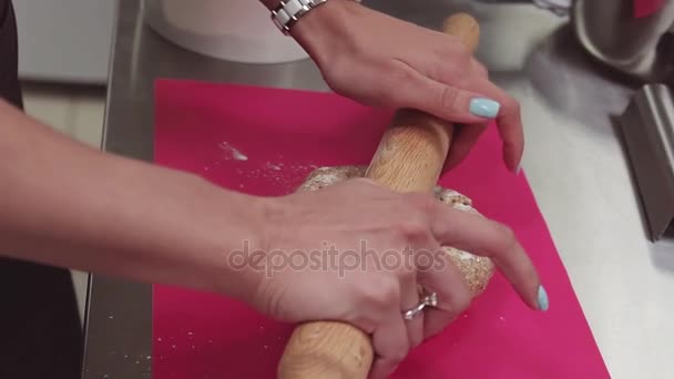 Manos de pastelero utilizando rodillo en la masa sobre tabla de cortar rosa
 - Metraje, vídeo