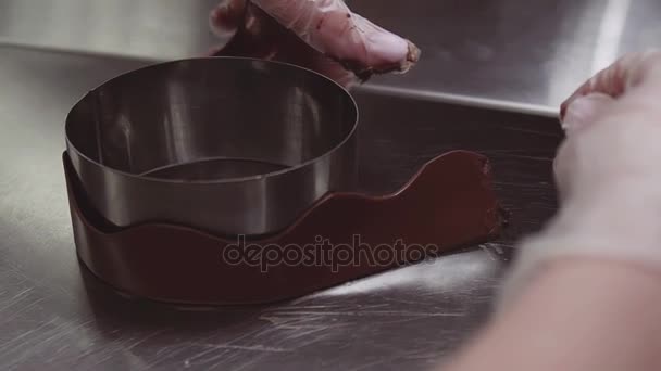 Mãos de confeiteiro envolve decoração de chocolate em torno de assadeira de metal
 - Filmagem, Vídeo