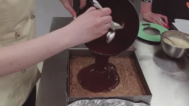 Cukrász önti olvasztott csokoládét a bisquit sütés tálca - Felvétel, videó