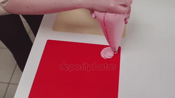 Жіночий кондитерський кіт стискає кондитерський мішок, роблячи товари на червоній обробній дошці
 - Кадри, відео