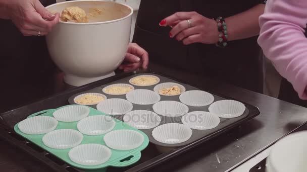 Desszert baker kézzel hozza tésztát Muffin pergamen poharak a tepsibe - Felvétel, videó