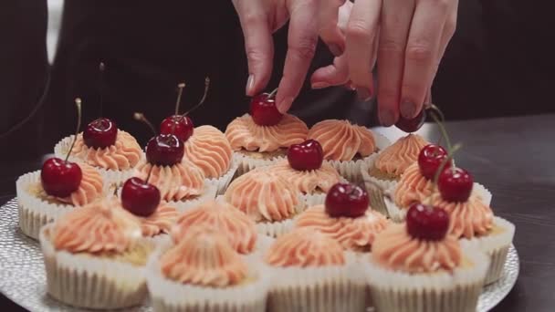 As mãos de confeiteiro decoram topos de nata de bolos com bagas de cereja
 - Filmagem, Vídeo