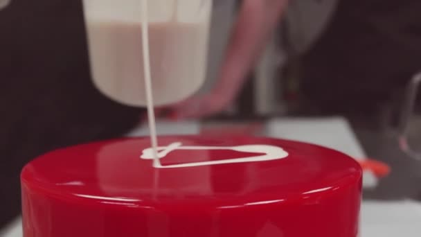 Кондитер наливает крем на торт красное зеркало глазури глазури из мерной чашки
 - Кадры, видео
