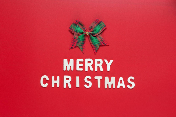 MERRY CHRISTMAS words with ribbon bow on red background - Fotoğraf, Görsel