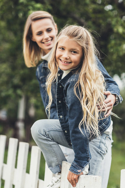 mother and daughter on fence  - Photo, image