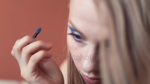 Привлекательная девушка делает ее макияж ставит на синие тени глаза
 - Кадры, видео