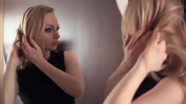 Молодая привлекательная блондинка веселая девушка смотрит в зеркало, щекочет макияж
 - Кадры, видео