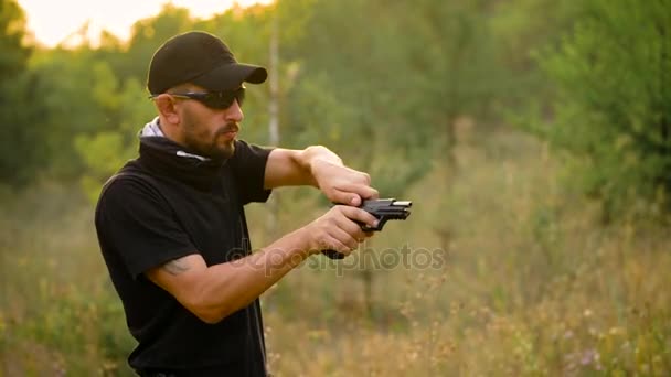 Νεαρός άνδρας στο καμουφλάζ γυρίσματα από ένα πυροβόλο όπλο, κοντινό πλάνο - Πλάνα, βίντεο
