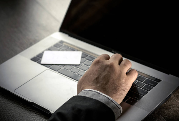 Крупним планом біла електронна картка, що лежить на клавіатурі комп'ютера та наборі рук
 - Фото, зображення