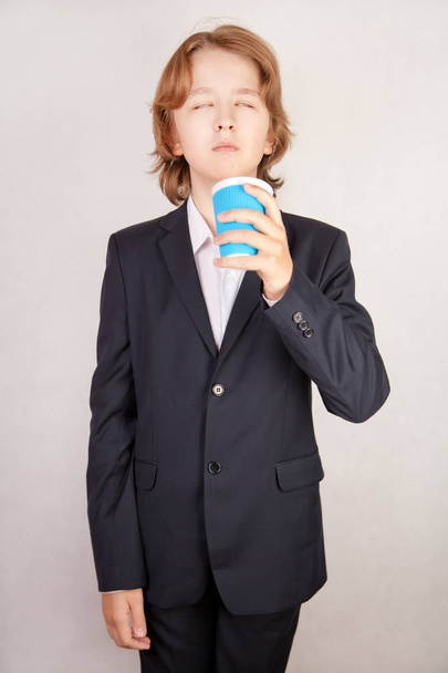 cansado estresse adolescente menino vestindo terno de negócios em pé no fundo do estúdio branco sozinho
 - Foto, Imagem