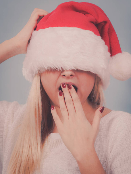 Yawning woman santa claus covers her eyes - 写真・画像