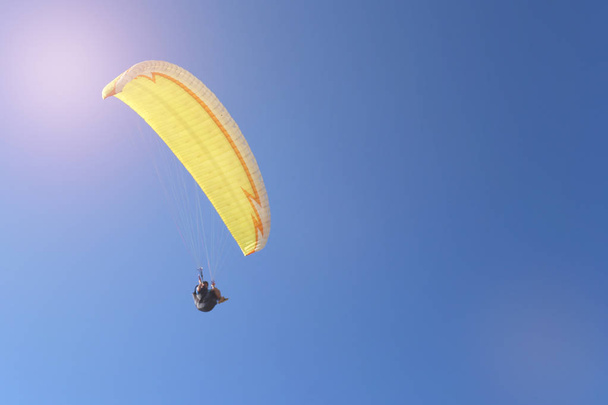 Man flying on a paraglider on the blue sky background - Foto, imagen