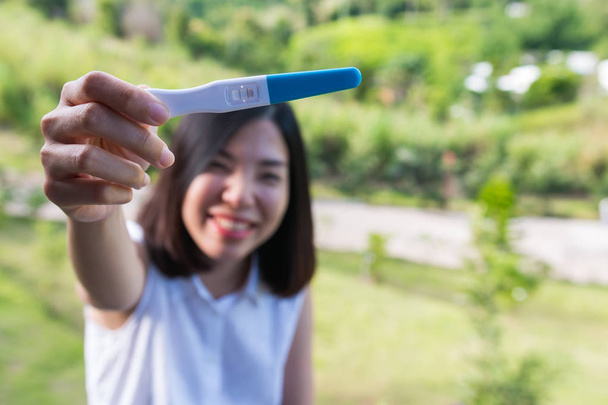 une jeune femme aux cheveux courts souriant et montrant le test de grossesse
 - Photo, image