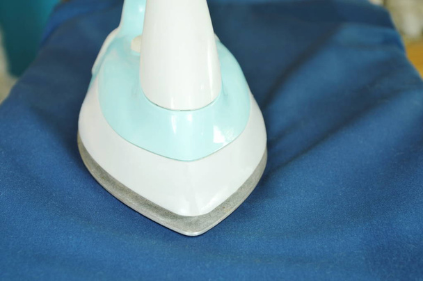  blaues automatisches Bügeleisen-Presstuch auf Bügelbrett - Foto, Bild