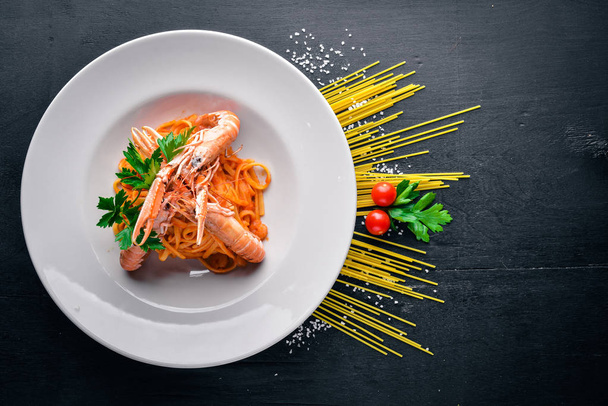 Pasta and tiger shrimp in tomato sauce. Italian traditional food. On a wooden background. Top view. Free space for your text. - Fotoğraf, Görsel