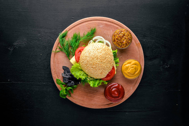 Hamburger with cheese, meat and green onions on Wooden background. Top view. Free space. - Foto, afbeelding