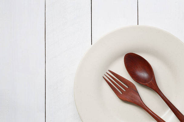 Plate and spoon on white wood floor. - Photo, Image