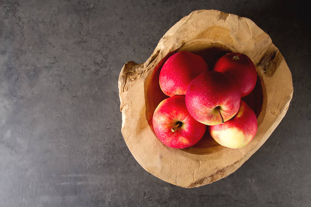 Ripe juicy apple in a wooden bowl. Dark background. Space for te - Fotó, kép