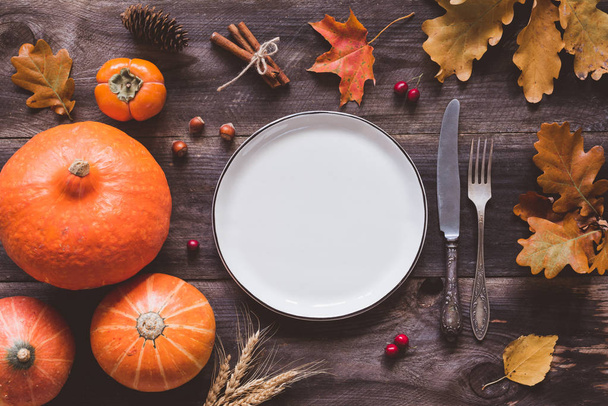 Cenário de mesa de ação de graças de outono com prato vazio, talheres e abóboras
 - Foto, Imagem