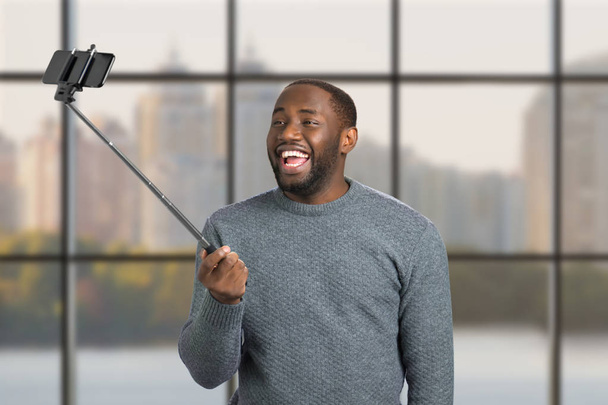 Człowiek śmiechu biorąc selfie z monopod. - Zdjęcie, obraz