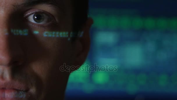 Portret van Man programmeur hacker met groene code tekens nadenken over zijn gezicht met een computerscherm op de achtergrond - Video