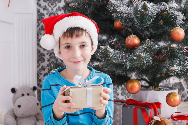 Lindo chico en santa sombrero desenvolver regalos de Navidad
 - Foto, imagen