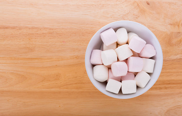 Marshmallows in a bowl on wooden background - Фото, изображение