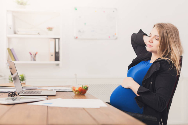 Pregnant businesswoman eating salad at office - Фото, изображение