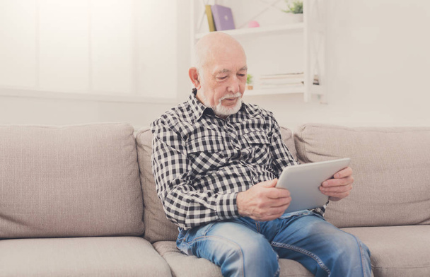 Senior homme lisant des nouvelles sur tablette numérique
 - Photo, image