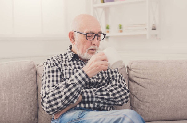 Senior man having cup of coffee in living room - Foto, imagen