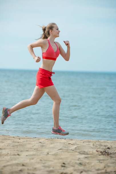 Young lady running at the sunny summer sand beach. Workout.  Jog - Foto, Bild