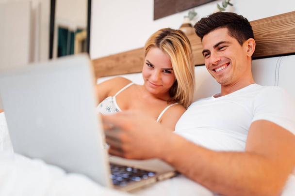 Couple in bed using laptop - 写真・画像