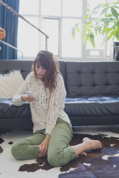 Cheerful woman speaking on mobile phone, sitting on living room - Photo, Image
