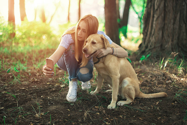 smiling young woman with dog outdoors in autumn making selfie - Photo, Image