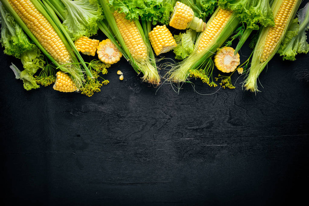 Corn. Raw Vegetables On a black wooden background. Top view. Free space for your text. - Foto, Imagen