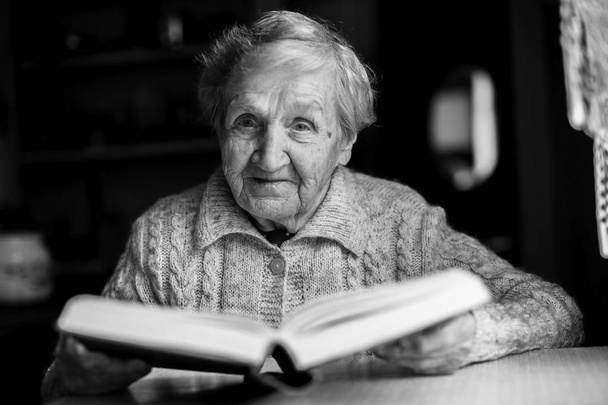 Idős asszony ül egy tabl - Fotó, kép