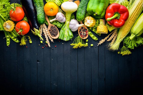 A large selection of raw fresh vegetables and spices. On a black wooden background. Top view. Free space for your text. - Foto, afbeelding