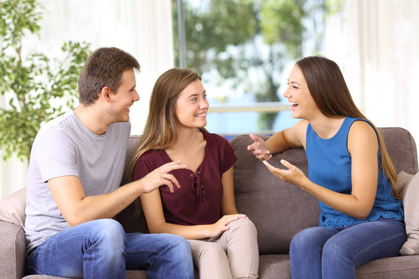 Three joyful friends talking on a couch at home - Foto, imagen