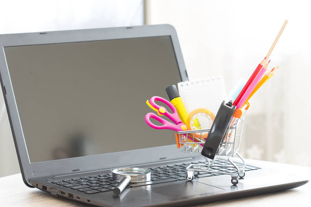 School and stationery material in shopping cart top laptop - 写真・画像