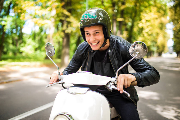 Moda bell'uomo alla guida di uno scooter in casco nel centro storico
 - Foto, immagini