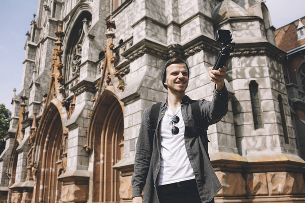 Happy traveller is making selfie near the cathedral building in the city - Foto, afbeelding